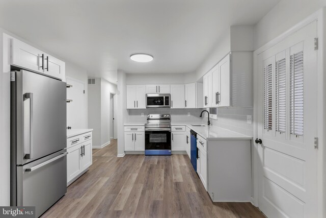 708 S Broad St, Mechanicsburg, PA 17055 - kitchen with stainless steel appliances, white cabinets, light countertops, light wood-type flooring, and tasteful backsplash