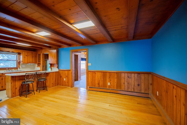 121 E James St, Winchester, VA 22601 - kitchen with light wood-style flooring, wainscoting, a baseboard heating unit, light countertops, and brown cabinetry