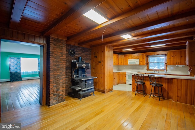 121 E James St, Winchester, VA 22601 - kitchen featuring white appliances, a wood stove, light wood-type flooring, a wooden ceiling with exposed beams, and light countertops