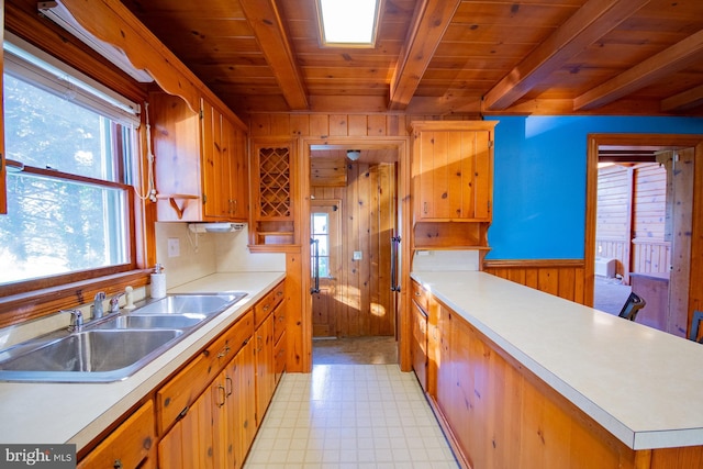 121 E James St, Winchester, VA 22601 - kitchen featuring light floors, a wooden ceiling with exposed beams, light countertops, wood walls, and brown cabinetry