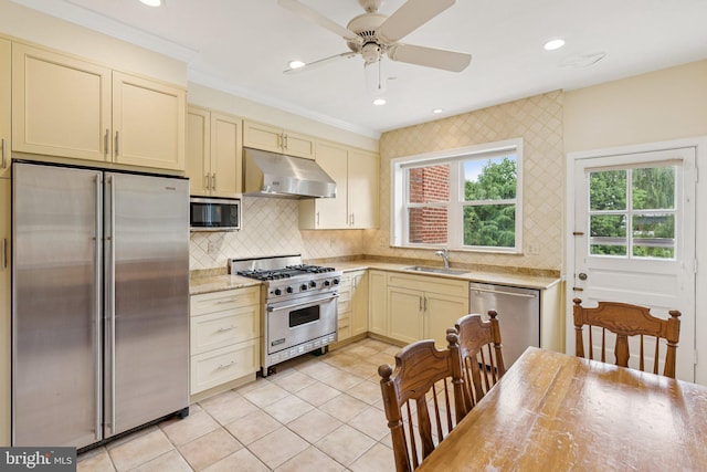 3917 Fessenden St NW, Washington, DC 20016 - kitchen featuring high end appliances, cream cabinetry, under cabinet range hood, light tile patterned flooring, and tasteful backsplash