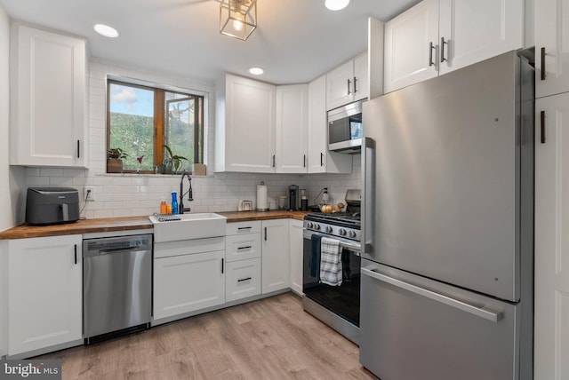2229 S Darien St, Philadelphia, PA 19148 - kitchen featuring appliances with stainless steel finishes, butcher block countertops, white cabinetry, light wood-style flooring, and tasteful backsplash