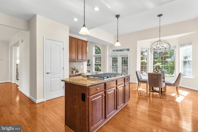 4509 Rhett Ln, Fairfax, VA 22030 - kitchen featuring light wood-style flooring, pendant lighting, light stone countertops, tasteful backsplash, and a kitchen island