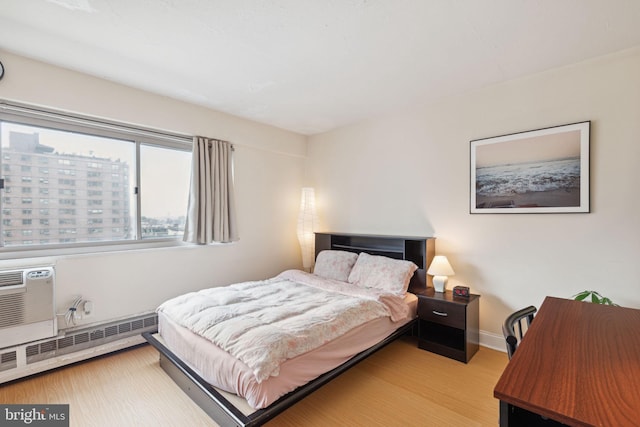 2101 Chestnut St Unit 909, Philadelphia, PA 19103 - bedroom featuring a baseboard radiator, wood finished floors, and a wall unit AC