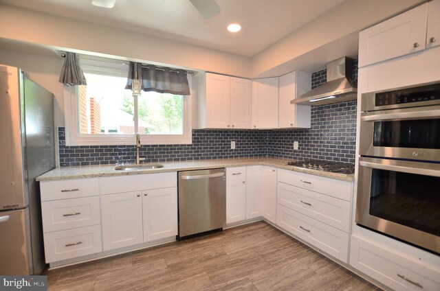 207 Maryland Ave, Newport, DE 19804 - kitchen with appliances with stainless steel finishes, wall chimney range hood, white cabinetry, tasteful backsplash, and recessed lighting