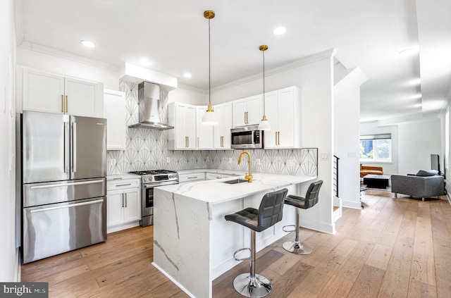 1922 1st St NW Unit B, Washington, DC 20001 - kitchen featuring appliances with stainless steel finishes, wall chimney exhaust hood, a peninsula, white cabinetry, and light stone counters
