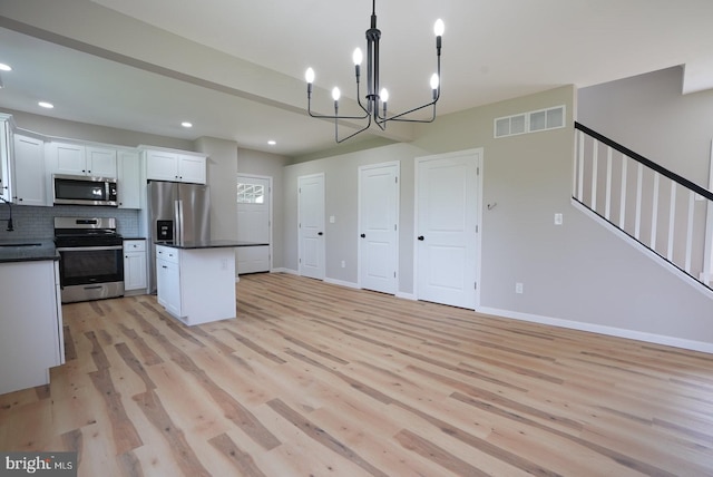 2 Schooner Landing Rd, Millville, NJ 08332 - kitchen with appliances with stainless steel finishes, dark countertops, light wood finished floors, a center island, and white cabinets
