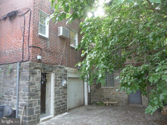 537 E Comly St, Philadelphia, PA 19120 - view of side of home with brick siding, concrete driveway, an attached garage, and stone siding