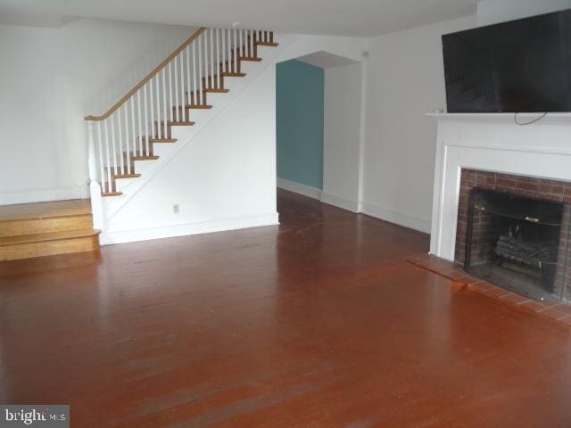 537 E Comly St, Philadelphia, PA 19120 - unfurnished living room featuring a tiled fireplace, stairway, and wood finished floors