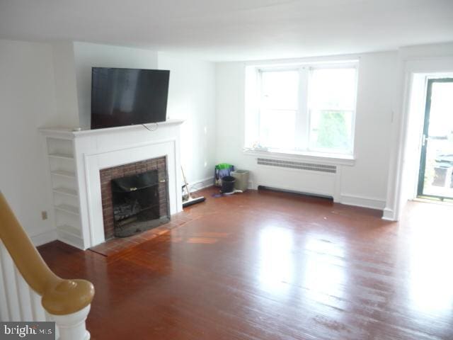 537 E Comly St, Philadelphia, PA 19120 - living room with radiator heating unit, a fireplace with flush hearth, and wood finished floors