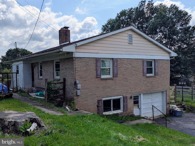 44 Chestnut St, Adamstown, PA 19501 - back of property featuring a chimney, brick siding, an attached garage, and driveway