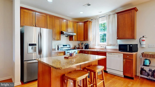 47 Buck Rd, Mays Landing, NJ 08330 - kitchen with appliances with stainless steel finishes, under cabinet range hood, a kitchen island, light wood-type flooring, and a breakfast bar