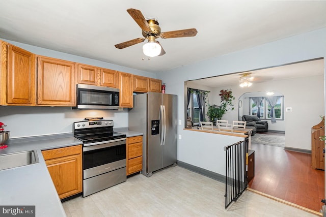5200 Daybreak Ct, Baltimore, MD 21206 - kitchen with stainless steel appliances, a ceiling fan, light wood-style flooring, open floor plan, and arched walkways