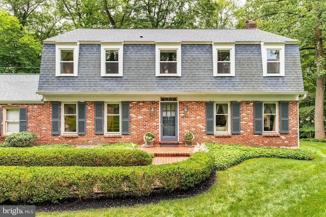 544 N Wayne Ave, Wayne, PA 19087 - view of front of home with a shingled roof, a chimney, a front lawn, a gambrel roof, and brick siding