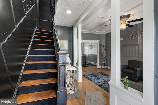 16 N Morley St, Baltimore, MD 21229 - stairway with ornate columns, ceiling fan, wood finished floors, a decorative wall, and a textured ceiling