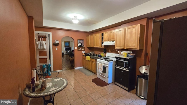 1260 E State St, Trenton, NJ 08609 - kitchen with white range with gas stovetop, under cabinet range hood, arched walkways, and light tile patterned floors