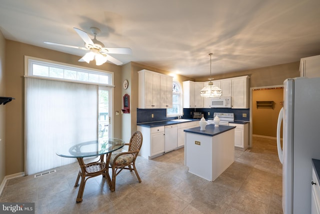 5900 Wayside Dr, Macungie, PA 18062 - kitchen with white appliances, a kitchen island, dark countertops, a ceiling fan, and healthy amount of natural light