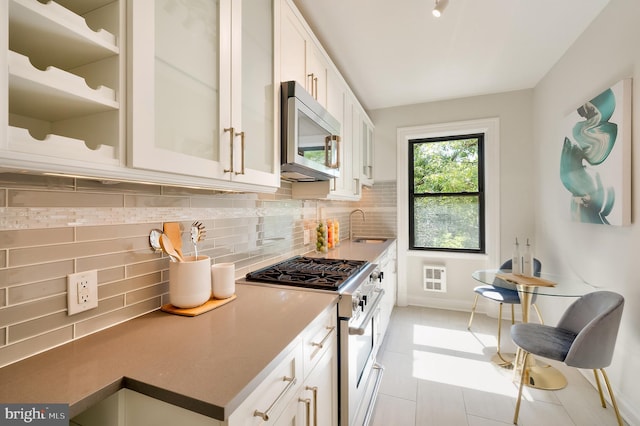 3100 Connecticut Ave NW Unit 434, Washington, DC 20008 - kitchen featuring high end range, stainless steel microwave, backsplash, white cabinets, and glass insert cabinets