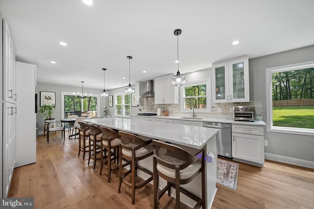 14731 Conway Dr, Manassas, VA 20112 - kitchen with stainless steel dishwasher, wall chimney range hood, white cabinetry, healthy amount of natural light, and recessed lighting