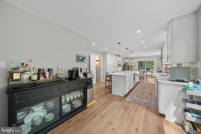 14731 Conway Dr, Manassas, VA 20112 - kitchen featuring a kitchen bar, white cabinetry, light countertops, light wood finished floors, and decorative light fixtures