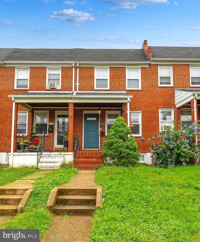 336 Imla St, Baltimore, MD 21224 - view of property featuring brick siding, covered porch, and a front lawn