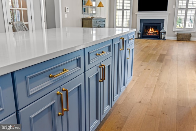 806 Dunfer Hill Rd, Severna Park, MD 21146 - kitchen with blue cabinetry, a fireplace with flush hearth, light wood-type flooring, and light countertops