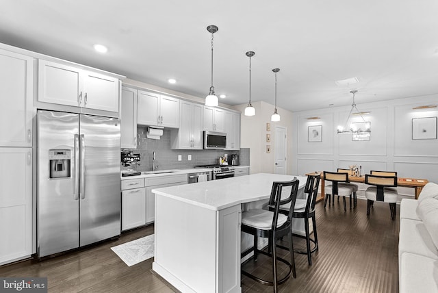 23230 Milltown Knoll Sq Unit 106, Ashburn, VA 20148 - kitchen with appliances with stainless steel finishes, a kitchen island, a kitchen bar, dark wood-style floors, and tasteful backsplash