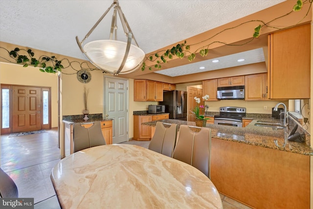 2700 Moores Valley Dr, Baltimore, MD 21209 - kitchen featuring appliances with stainless steel finishes, vaulted ceiling, dark stone counters, a peninsula, and a textured ceiling
