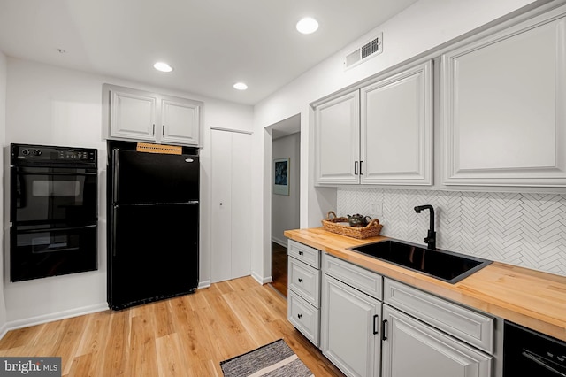 6128 Buckingham Manor Dr, Baltimore, MD 21210 - kitchen featuring black appliances, wood counters, tasteful backsplash, light wood-type flooring, and white cabinets