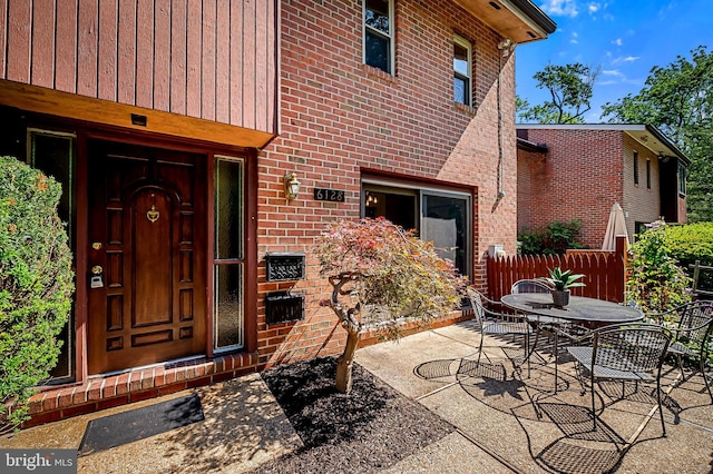 6128 Buckingham Manor Dr, Baltimore, MD 21210 - view of exterior entry featuring brick siding, outdoor dining area, and a patio