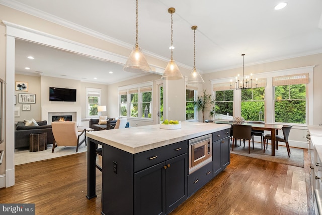 2407 N Nelson St, Arlington, VA 22207 - kitchen featuring stainless steel microwave, a warm lit fireplace, a chandelier, light countertops, and dark wood-style floors