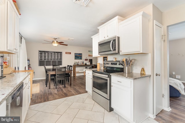 30 Bunker Ln, Etters, PA 17319 - kitchen with appliances with stainless steel finishes, ceiling fan, white cabinetry, light stone counters, and light wood-style flooring
