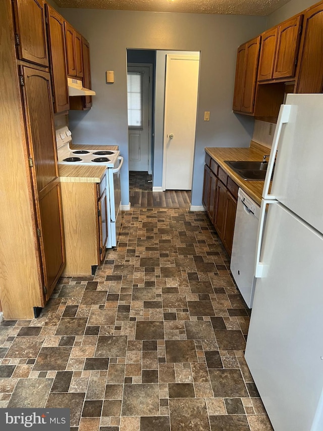 2177 Fawn Ct, Waldorf, MD 20602 - kitchen with white appliances, under cabinet range hood, light countertops, brick patterned floors, and brown cabinetry