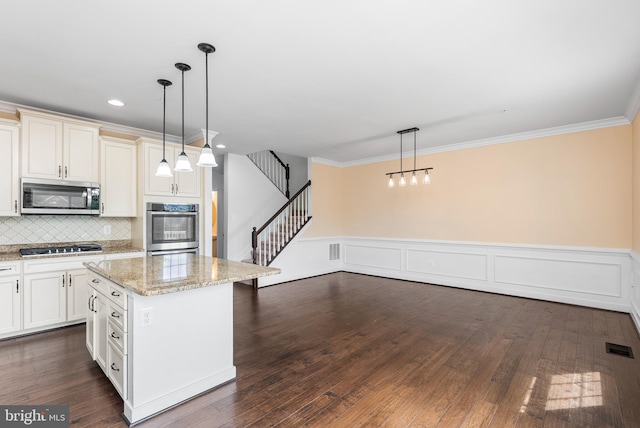 9 Fila Way, Sparks Glencoe, MD 21152 - kitchen featuring appliances with stainless steel finishes, a kitchen island, ornamental molding, light stone countertops, and tasteful backsplash