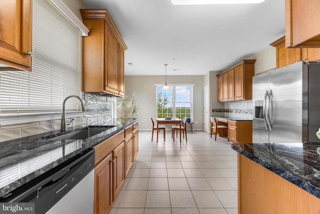 7315 Brookview Rd Unit 306, Elkridge, MD 21075 - kitchen featuring appliances with stainless steel finishes, decorative backsplash, brown cabinetry, decorative light fixtures, and dark stone counters