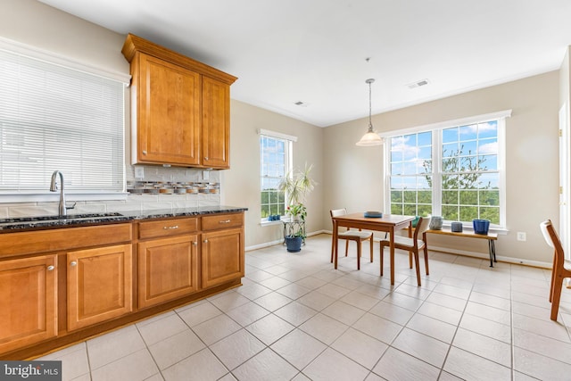 7315 Brookview Rd Unit 306, Elkridge, MD 21075 - kitchen with healthy amount of natural light, brown cabinets, backsplash, and dark stone counters