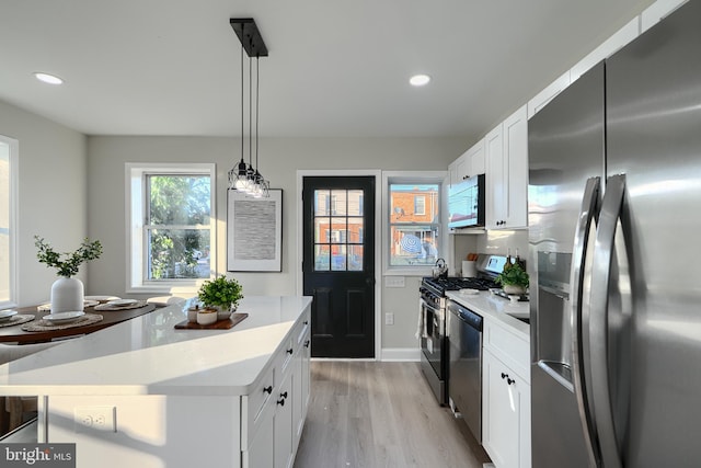 3027 Seamon Ave, Baltimore, MD 21225 - kitchen featuring appliances with stainless steel finishes, light wood-style floors, light countertops, white cabinets, and a center island