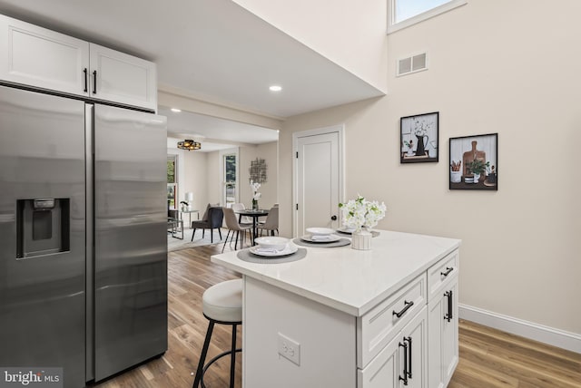 33 Main St, Pilesgrove, NJ 08098 - kitchen featuring stainless steel refrigerator with ice dispenser, a breakfast bar, white cabinetry, light wood-type flooring, and a kitchen island