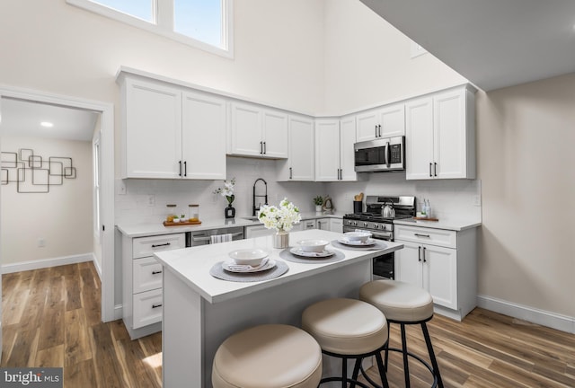 33 Main St, Pilesgrove, NJ 08098 - kitchen with appliances with stainless steel finishes, a breakfast bar, light countertops, wood finished floors, and a high ceiling