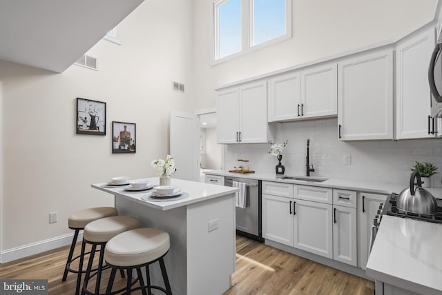 33 Main St, Pilesgrove, NJ 08098 - kitchen featuring stainless steel dishwasher, a kitchen island, tasteful backsplash, a breakfast bar area, and light countertops
