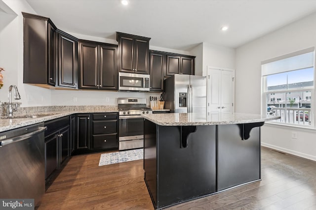 515 Quarry Point Rd, Malvern, PA 19355 - kitchen with appliances with stainless steel finishes, dark wood-style flooring, a kitchen island, light stone counters, and a kitchen breakfast bar