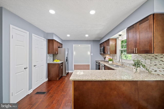 6112 Hillview Ct, Manassas, VA 20112 - kitchen featuring appliances with stainless steel finishes, dark wood finished floors, a peninsula, light stone counters, and backsplash