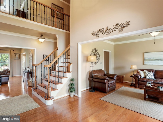 22124 Whitestone Ct, Smithsburg, MD 21783 - living room featuring wood finished floors, a towering ceiling, stairs, and crown molding