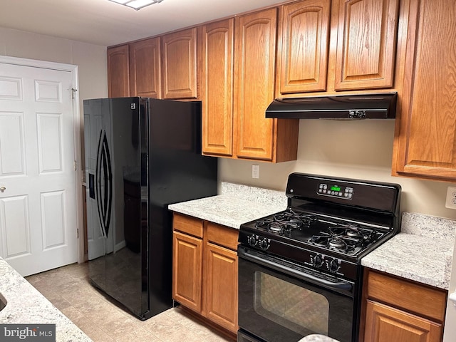 8980 Harrover Pl Unit 80B, Lorton, VA 22079 - kitchen with black appliances, under cabinet range hood, brown cabinets, light stone counters, and light tile patterned floors