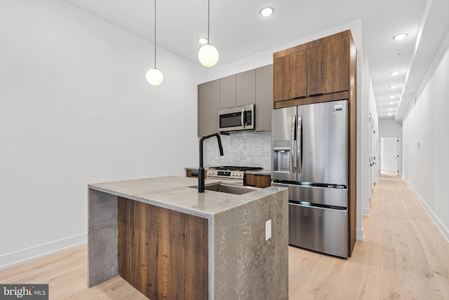 1338 N Franklin St, Philadelphia, PA 19122 - kitchen with stainless steel appliances, backsplash, light wood finished floors, light stone countertops, and a kitchen island with sink