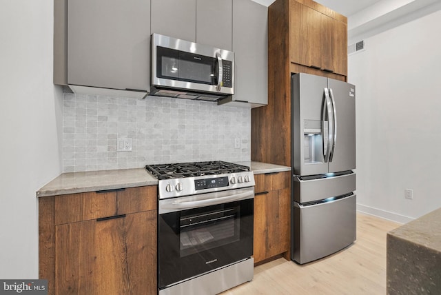 1338 N Franklin St, Philadelphia, PA 19122 - kitchen with appliances with stainless steel finishes, light wood-type flooring, modern cabinets, decorative backsplash, and brown cabinetry