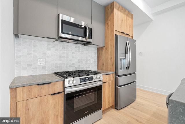 1338 N Franklin St, Philadelphia, PA 19122 - kitchen with stainless steel appliances, modern cabinets, light wood-type flooring, dark stone counters, and tasteful backsplash