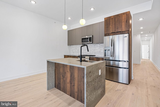 1338 N Franklin St, Philadelphia, PA 19122 - kitchen with appliances with stainless steel finishes, light wood finished floors, tasteful backsplash, an island with sink, and pendant lighting