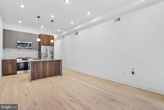 1338 N Franklin St, Philadelphia, PA 19122 - kitchen with appliances with stainless steel finishes, recessed lighting, tasteful backsplash, a kitchen island with sink, and light wood finished floors