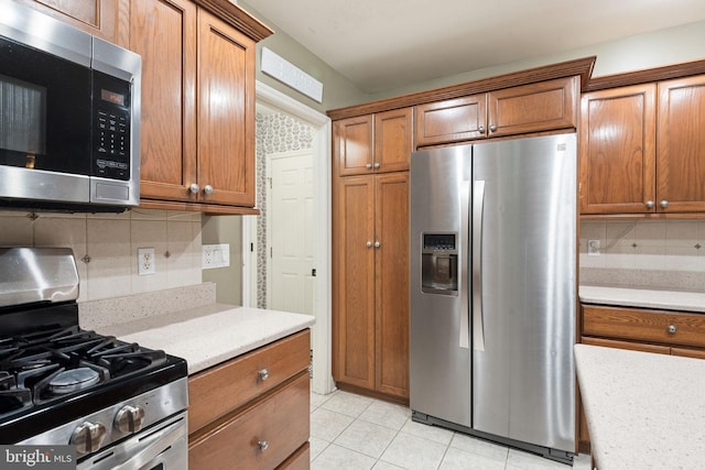 16 Fox Hollow Dr, Lancaster, PA 17602 - kitchen with stainless steel appliances, decorative backsplash, brown cabinetry, and light tile patterned floors